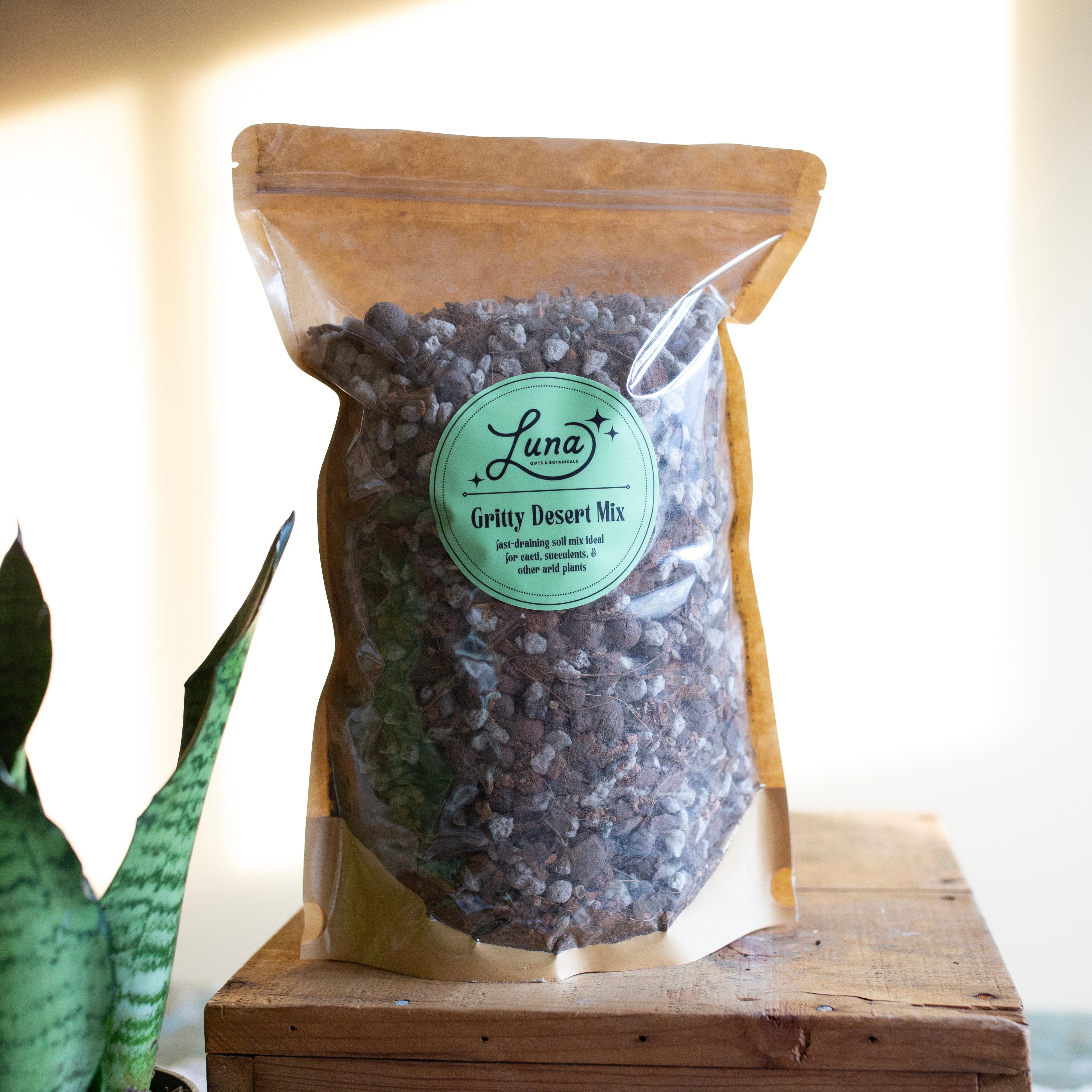 Bag of Luna Gritty Desert Mix on a wooden surface with a plant in the background